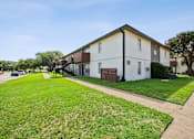 Thumbnail 20 of 23 - A white apartment building with a green lawn in front.