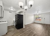Thumbnail 1 of 23 - A kitchen with a black fridge and wooden floors.