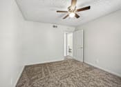 Thumbnail 7 of 23 - A room with a ceiling fan and carpeted floor.