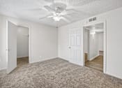 Thumbnail 9 of 23 - A room with a ceiling fan and carpeted floor.