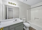 Thumbnail 11 of 23 - A white bathroom with a sink, toilet, and bathtub.