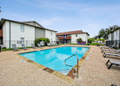Thumbnail 13 of 23 - A swimming pool surrounded by lounge chairs and apartment buildings.