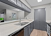 Thumbnail 7 of 22 - A modern kitchen with a sink, stove, and cabinets.