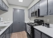 Thumbnail 4 of 22 - A kitchen with a black stove top oven and a black microwave above it.