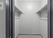 Thumbnail 22 of 22 - A small, empty walk-in closet with a carpeted floor and metal hangers.