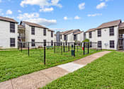 Thumbnail 16 of 22 - A row of white houses with green lawns and a clear blue sky.