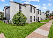 Thumbnail 20 of 22 - A white building with a green bush in front of it.