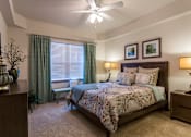 Thumbnail 10 of 40 - A bedroom with a large bed and a ceiling fan.