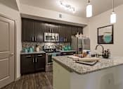 Thumbnail 2 of 40 - A kitchen with a granite countertop and dark brown cabinets.