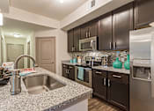 Thumbnail 1 of 40 - A kitchen with a sink, microwave, and refrigerator.