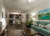 Thumbnail 8 of 40 - A living room with a green couch and a painting on the wall.