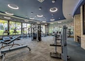 Thumbnail 27 of 40 - A gym with a variety of equipment including treadmills, weights, and exercise machines.