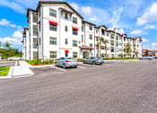 Thumbnail 39 of 40 - A row of apartment buildings with cars parked in front.