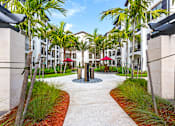 Thumbnail 35 of 40 - A walkway with a red umbrella in the middle of it.