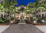 Thumbnail 38 of 40 - A building with a pathway and palm trees in front.