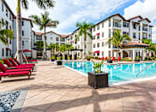 Thumbnail 31 of 40 - A pool surrounded by red chairs and palm trees.