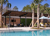 Thumbnail 31 of 47 - A pool area with a wooden building and palm trees.
