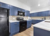 Thumbnail 6 of 20 - a kitchen with blue cabinets and a stove and a microwave
