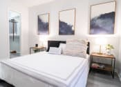 Thumbnail 8 of 20 - a bedroom with a white bed and paintings on the wall
