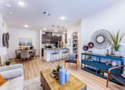 Thumbnail 3 of 32 - A modern living room with a kitchen in the background.