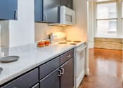 Thumbnail 2 of 13 - A kitchen with a white microwave above a stove and a white dishwasher.