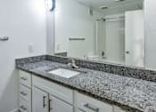 Thumbnail 6 of 13 - A bathroom with a granite countertop and white cabinets.