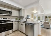 Thumbnail 19 of 33 - an open kitchen and living room with white cabinets and stainless steel appliances