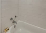 Thumbnail 19 of 20 - a bathroom with a white tub and a white tiled wall