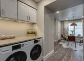Thumbnail 11 of 20 - a washer and dryer in a laundry room with a table and chairs