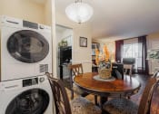Thumbnail 8 of 18 - a dining room with a table and chairs and a washer and dryer