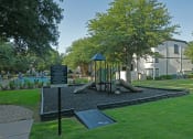 Thumbnail 15 of 29 - a park with a playground and a sign in front of a building