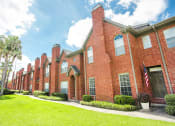 Thumbnail 20 of 22 - a brick building with a green lawn and palm trees