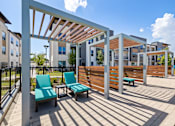 Thumbnail 18 of 33 - A patio with a white pergola and blue chairs.