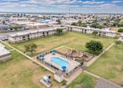 Thumbnail 23 of 23 - A large grassy area with a pool and apartment buildings in the background.