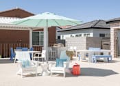 Thumbnail 17 of 19 - A patio with a table, chairs and an umbrella.