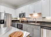 Thumbnail 4 of 21 - a modern kitchen with stainless steel appliances and white cabinets
