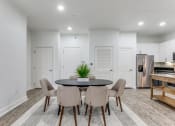 Thumbnail 6 of 21 - a living room with white walls and a table with chairs