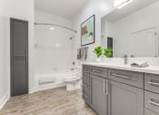 Thumbnail 11 of 21 - a bathroom with gray cabinets and a toilet and a shower