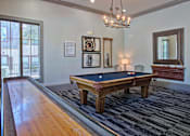 Thumbnail 21 of 28 - A pool table in a room with a chandelier and a mirror.