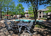 Thumbnail 14 of 28 - A table and chairs set is in the foreground of a pool area.