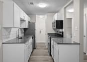 Thumbnail 1 of 29 - an empty kitchen with white cabinets and black counter tops