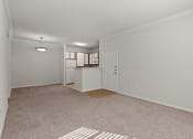 Thumbnail 9 of 26 - a spacious living room and kitchen with a carpeted floor and a white door