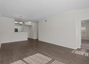 Thumbnail 1 of 26 - an empty living room with a hard wood floor and a kitchen
