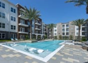 Thumbnail 29 of 34 - a swimming pool in front of an apartment building with palm trees