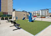 Thumbnail 18 of 31 - A playground with a blue slide and black benches.