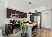 Thumbnail 21 of 31 - A modern kitchen with dark brown cabinets and stainless steel appliances.