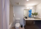 Thumbnail 27 of 31 - A bathroom with a toilet, sink, and mirror.