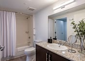Thumbnail 26 of 31 - A bathroom with a white toilet, sink, and a shower with a white curtain.