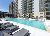 Thumbnail 31 of 37 - a swimming pool with lounge chairs in front of an apartment building