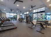 Thumbnail 27 of 37 - a gym with treadmills and other exercise equipment in a building with windows